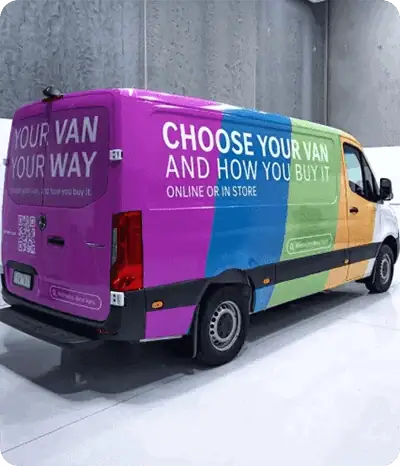 A colorful van wrapped in bright pink, blue, and orange advertising options to choose and buy a van online or in-store.